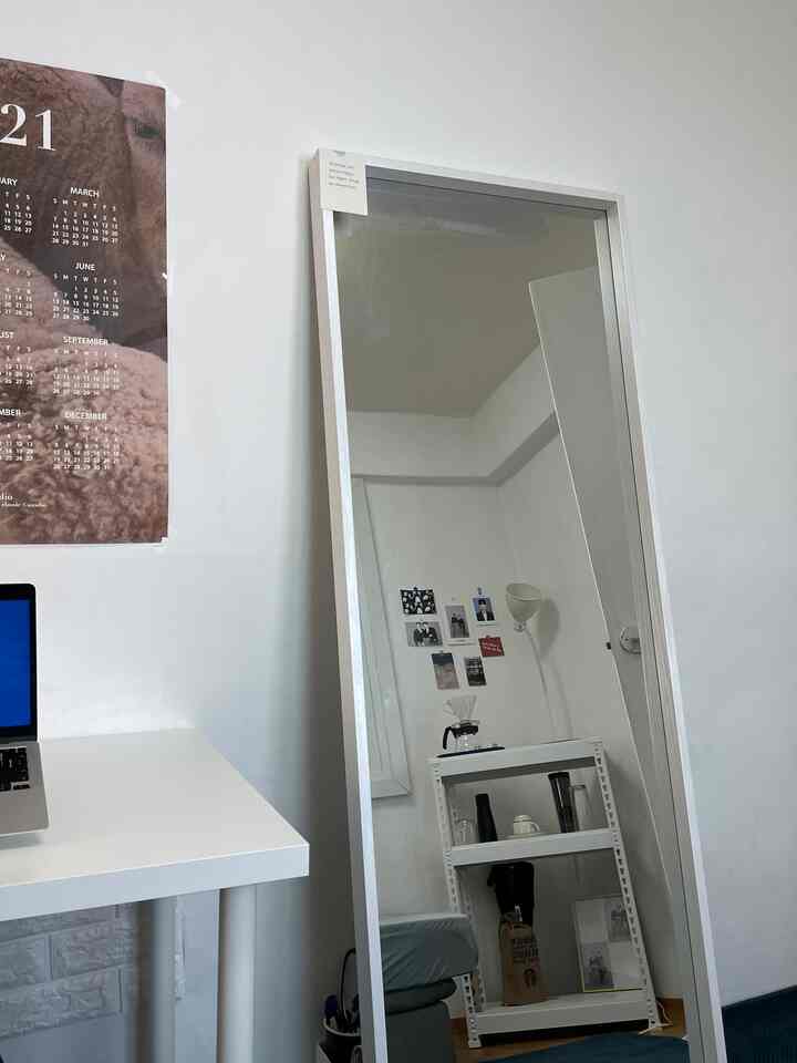 White-toned compact home office featuring desk, full-length mirror, and shelves with a minimalistic interior