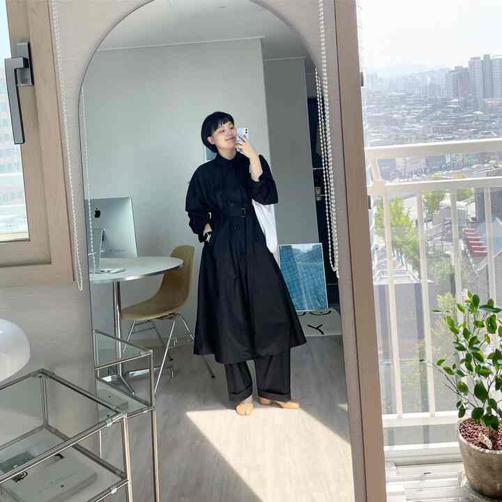 Modern space with white and wood tones showing a balcony view, featuring a large arch-shaped mirror and a round desk in a minimalistic interior