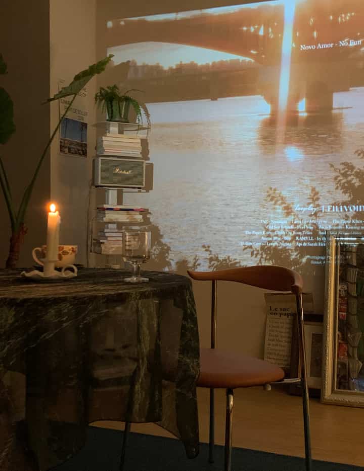 Warm vintage-toned living room featuring a projector screen on the wall, round table with candle creating cozy ambience