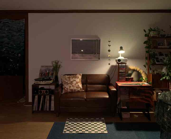 Living room with brown leather sofa and blinds, featuring retro turntable and rug in a cozy atmosphere