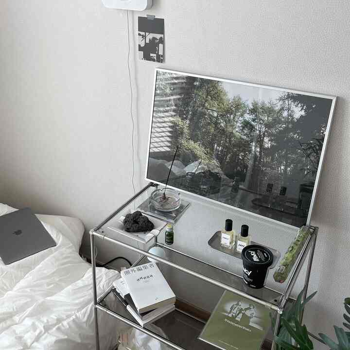 White and natural tone bedroom space featuring metal shelving and a poster with a simple and natural atmosphere