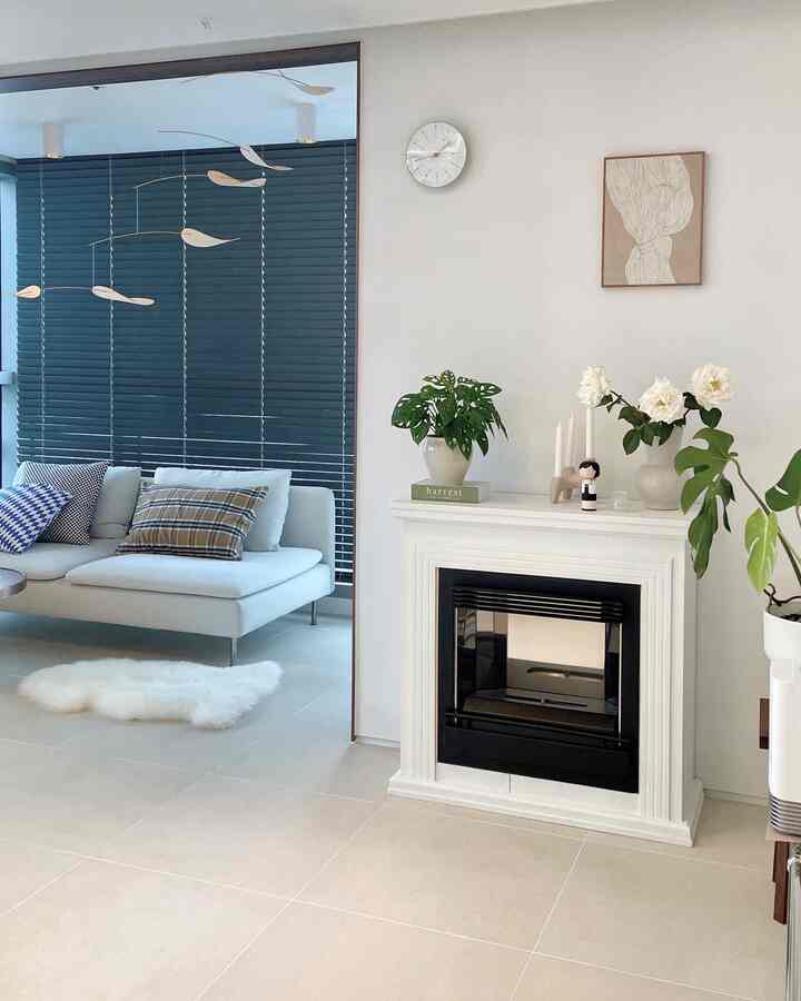 White and blue toned living room featuring mid-century modern sofa, mobile, and fireplace with a stylish ambiance