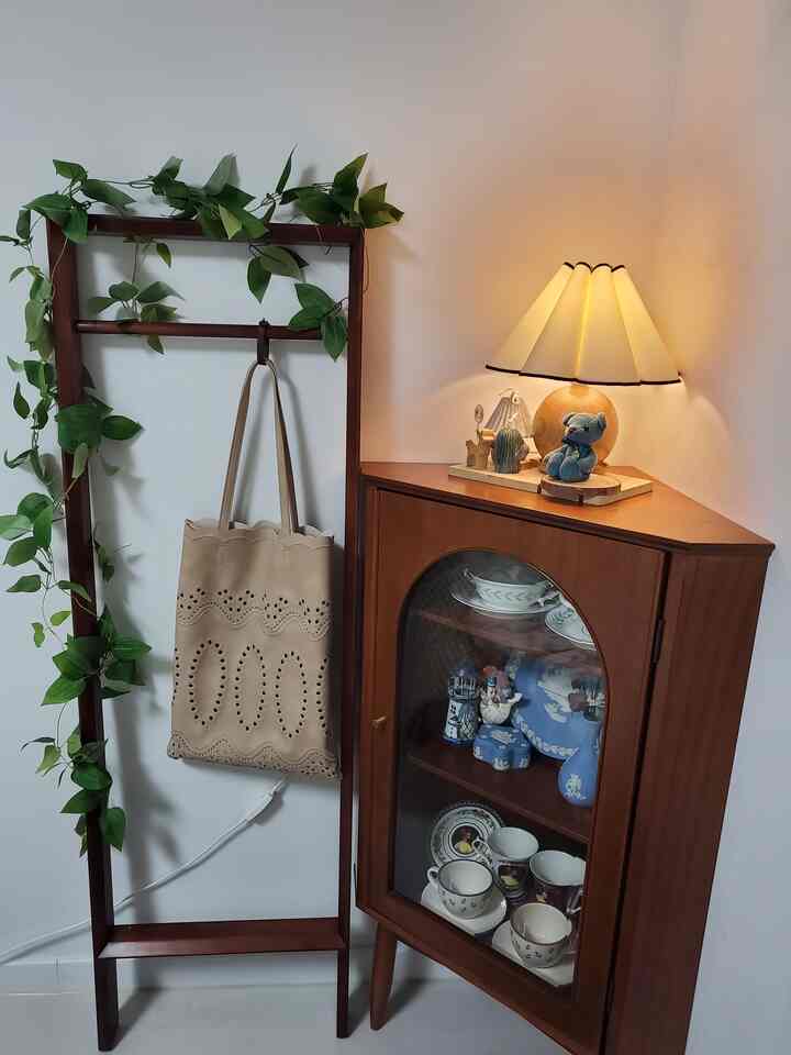 ナチュラルな色調のコーナーキャビネットがアーチ型の扉とともに配置されたコンパクトで整った収納空間