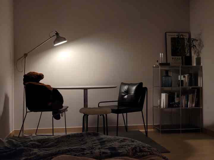 Wood tone and black accents define a simple, modern studio dining space with minimalist furniture and warm lighting