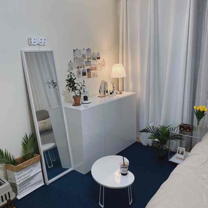 白と深い青のトーンの寝室、全身鏡とすっきりとした収納キャビネットが配置された、落ち着いたモダンな雰囲気のインテリア