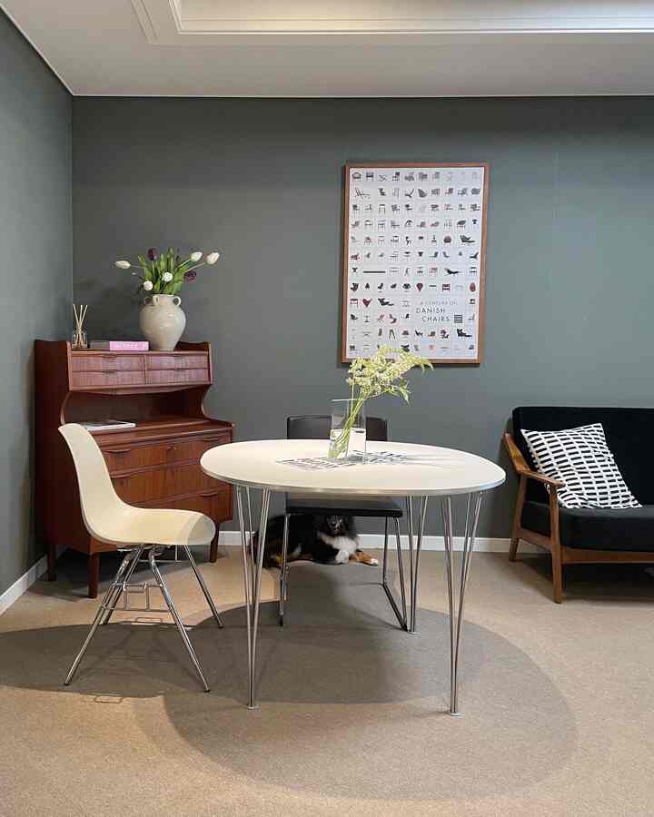 グレーの壁と丸いダイニングテーブル、ミッドセンチュリーモダン家具が配置されたヴィンテージ感のある家族室のインテリア