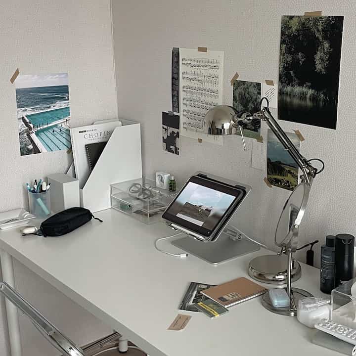 White-toned home office space featuring a desk with a tablet, silver desk lamp, and minimal, tidy decor
