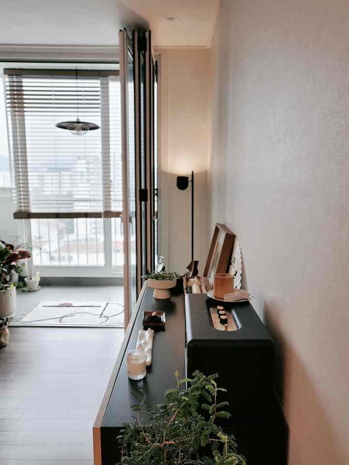 ウッドトーンとブラックが調和するリビング、キャビネットとブラインドが配置された雰囲気のあるインテリア