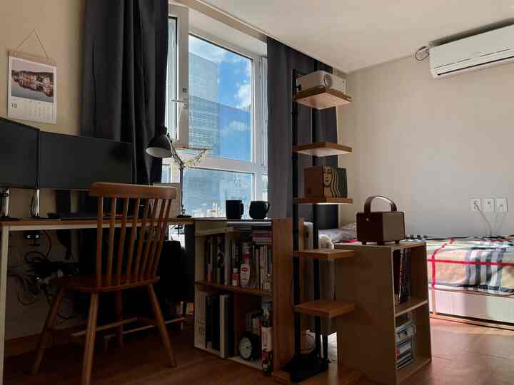 Wood tone and dark gray blackout curtains in a studio apartment home office and bedroom space