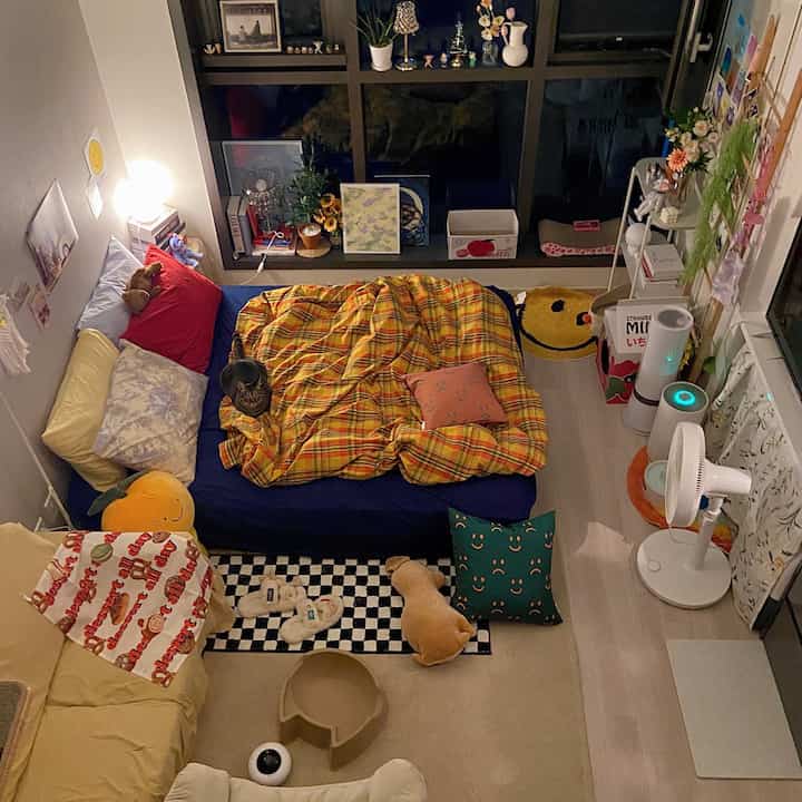 Cozy bedroom in warm yellow and blue tones featuring a central bed with checkered duvet cover, creating a comfortable atmosphere