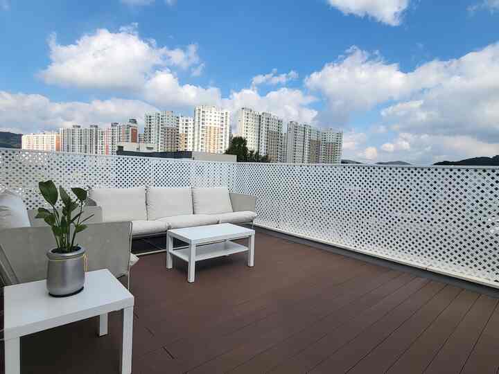 White lattice fence and brown wood-tone deck terrace featuring simple sofa and coffee table in a natural outdoor setting
