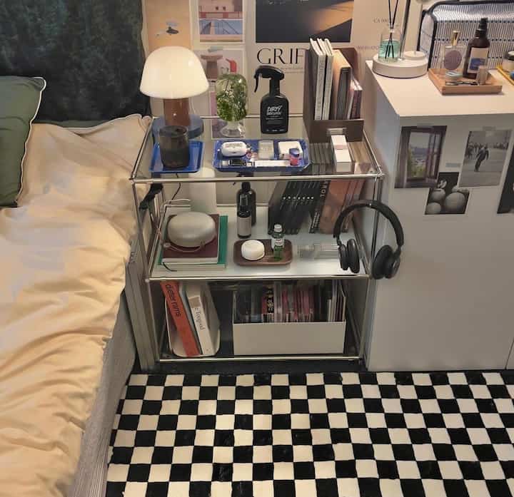 Black and white dominated bedroom nightstand area featuring transparent shelves and a checkered rug, creating a modern and clean atmosphere
