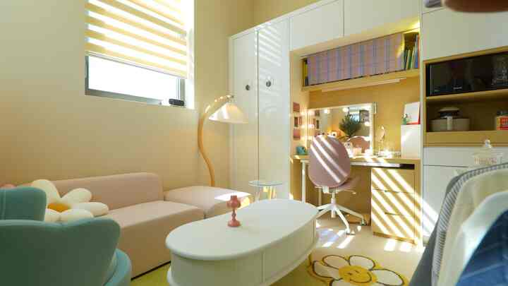 Cozy small living room in warm natural tones featuring white furniture and a pink chair with abundant sunlight