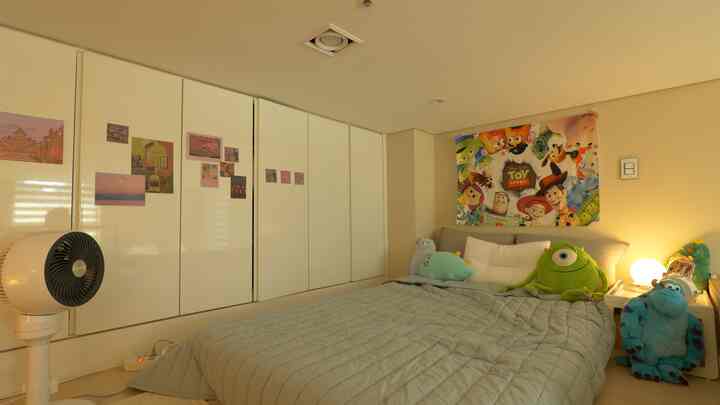 白とベージュの色調の6畳子供部屋、トイ・ストーリーポスターとカラフルなキャラクタークッションが配置された雰囲気のある寝室