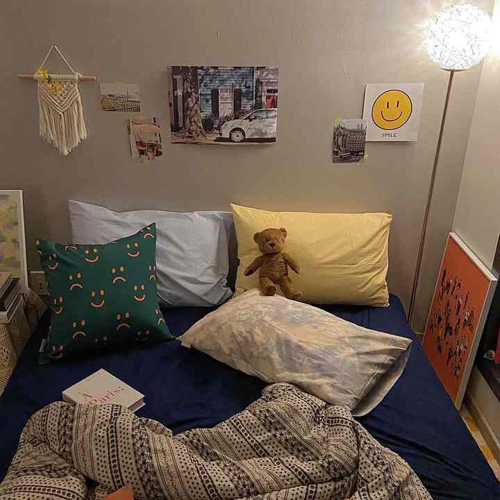 Navy and beige toned bedroom featuring assorted pillows and vintage-style posters creating a cozy atmosphere