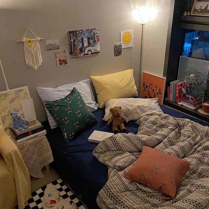 Navy and yellow toned bedroom featuring posters and a teddy bear creating a cozy atmosphere