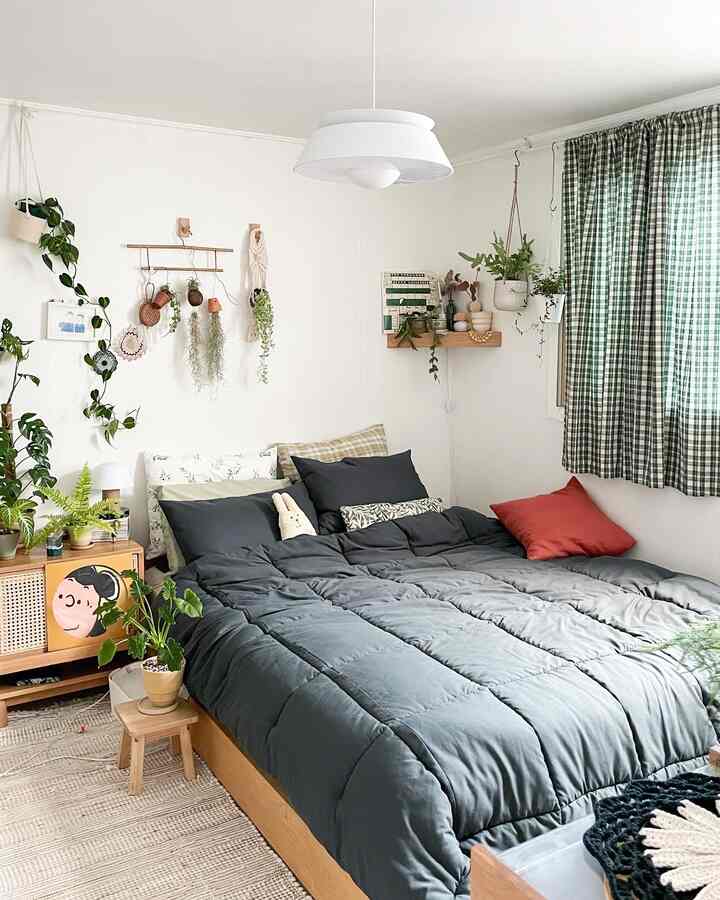 A natural wood-toned bedroom with green check curtains and plants, featuring a cozy dark bedding in a modern setting