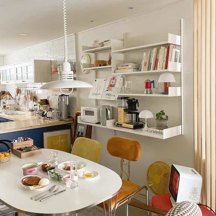 White-toned kitchen and dining room featuring shelves and home cafe elements with a warm atmosphere