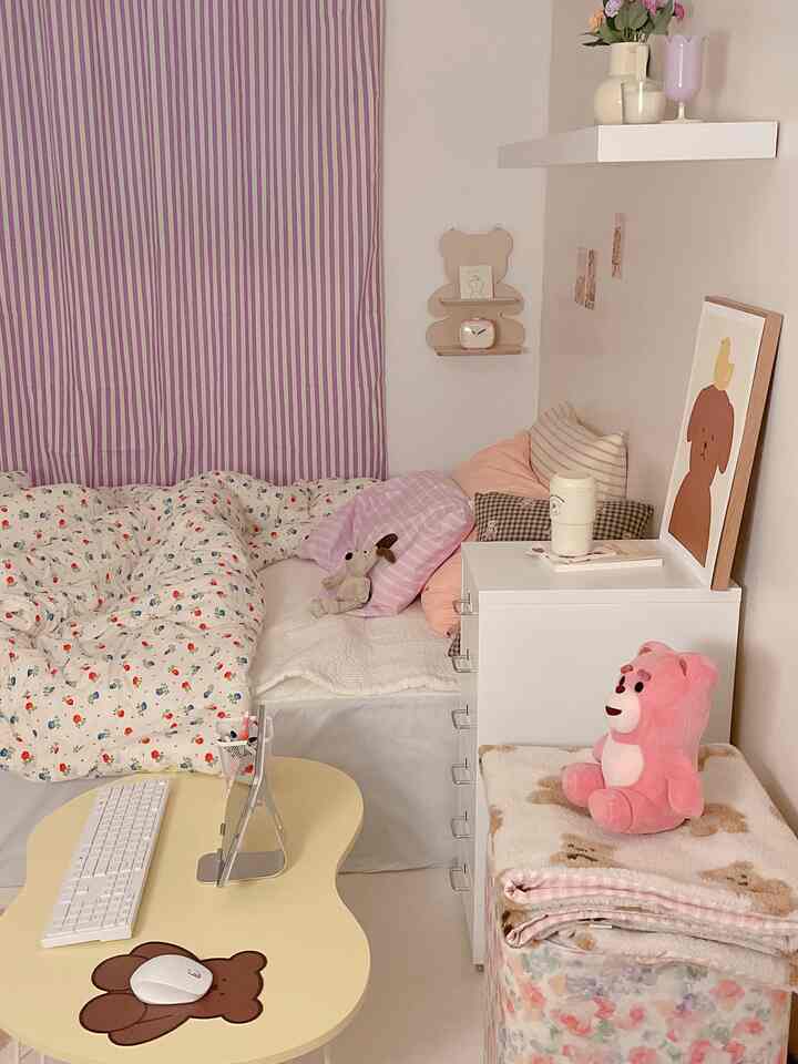 A cozy small bedroom in pink and white tones, featuring assorted cushions and teddy bear decorations