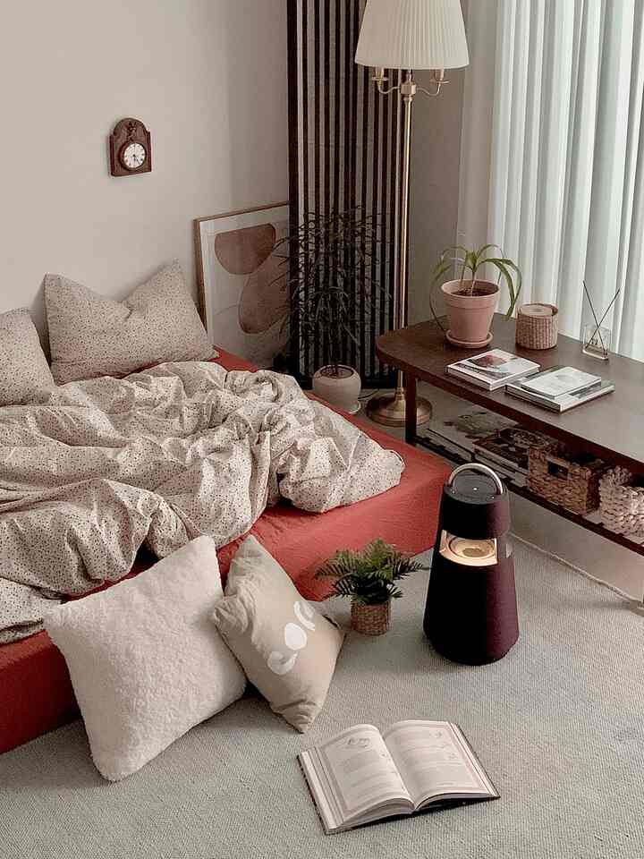A cozy, natural bedroom in burgundy and beige tones featuring cushions and a rug