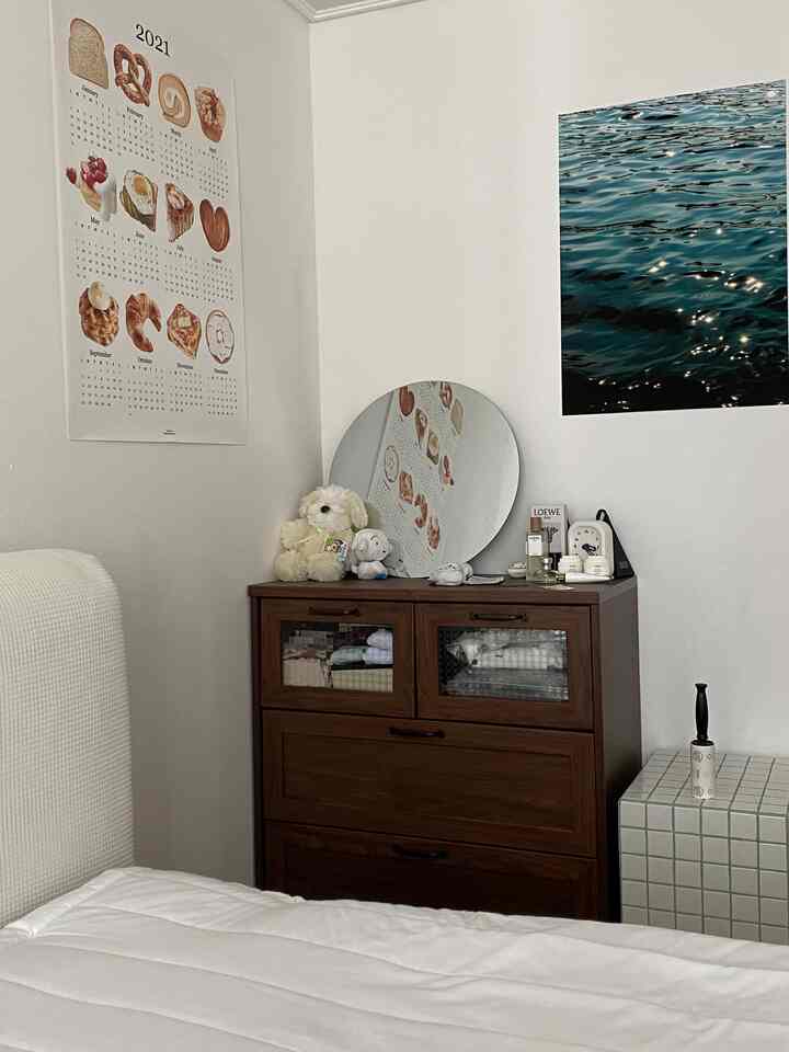 White and brown toned bedroom featuring a wooden dresser and posters creating a cozy, neat interior