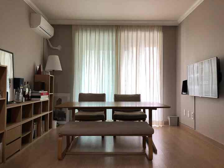 Beige and wood-toned two-person dining room featuring a large dining table and sheer curtains creating a natural atmosphere