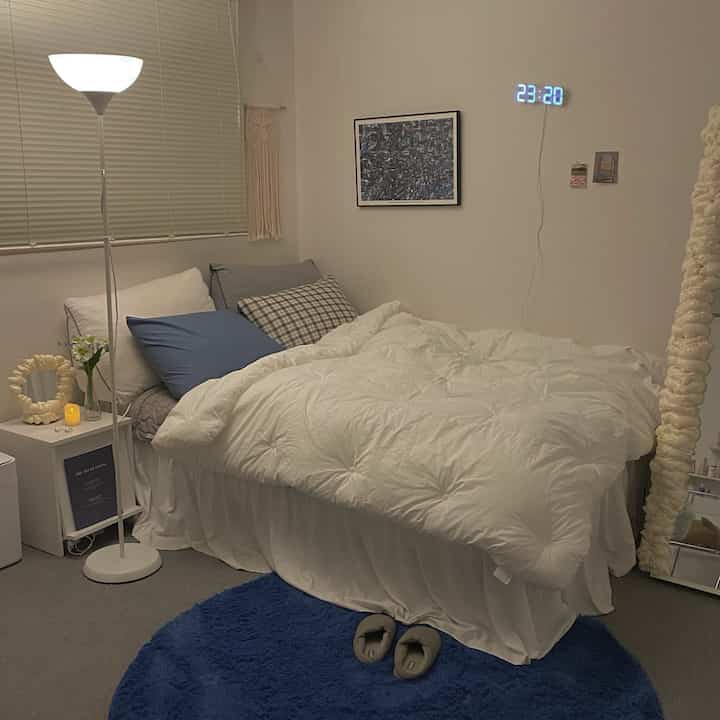 White and blue toned bedroom featuring a bed, framed poster, floor lamp, and cozy modern atmosphere
