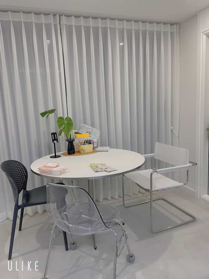 White and black toned compact dining room featuring a round dining table and diverse chairs in modern setting