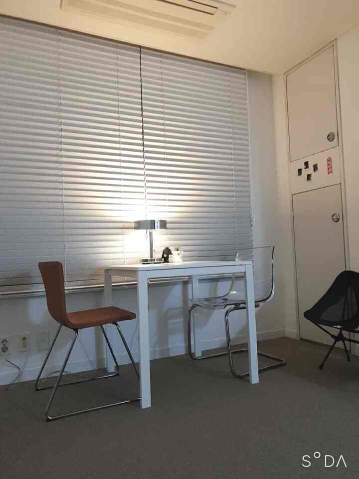 White and brown toned studio apartment dining area featuring a simple table set with warm, cozy atmosphere