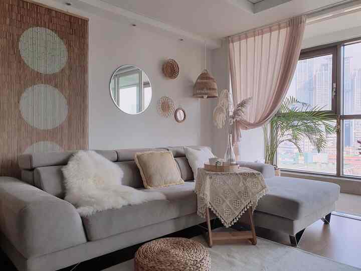 A living room with soft beige and natural wood tones, featuring rattan pendant light and crochet tablecloth for a cozy atmosphere