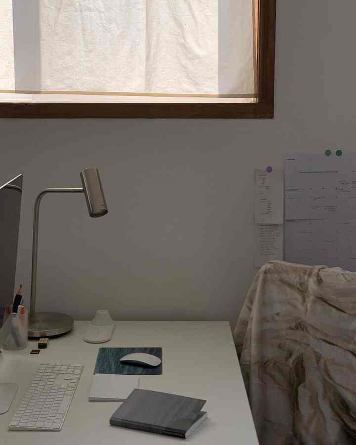 白とライトブラウンのトーンのホームオフィス、白いデスクとブラウンのパターンのブランケットが置かれた雰囲気のある空間