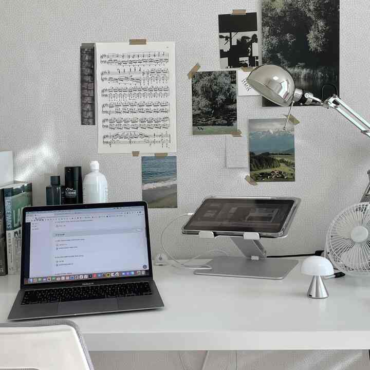 White and silver toned home office space featuring laptop and tablet stands with a clean work setup