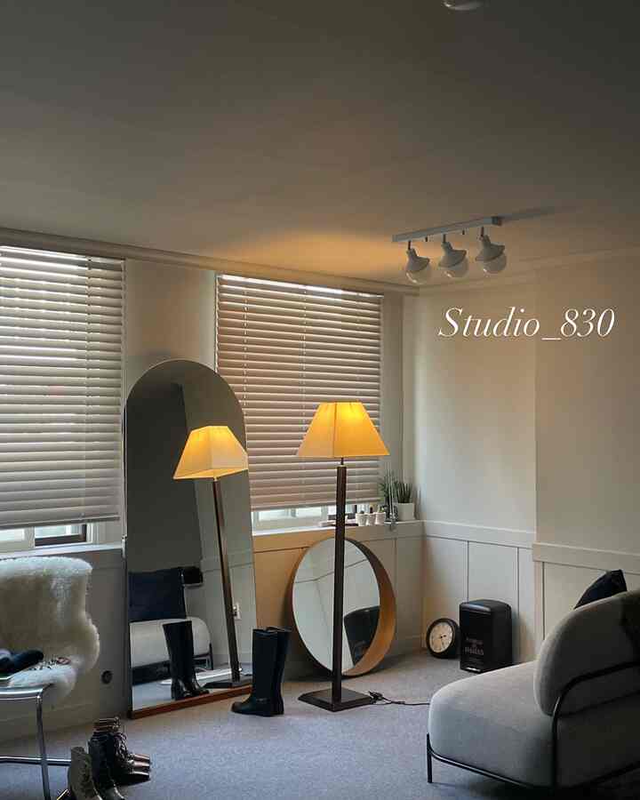 グレーのトーンと木製アクセントが調和したホームオフィス空間で、全身鏡とスタンドランプが温かみのある雰囲気のインテリア