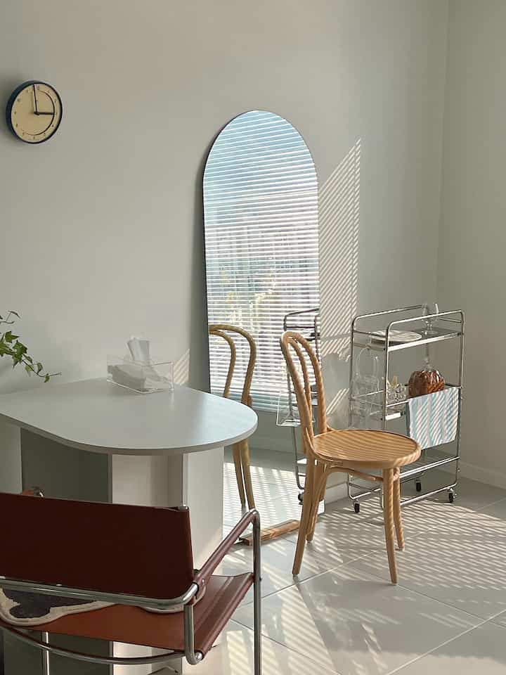 Bright living room in white and wood tones featuring an arch mirror and oval table with natural lighting