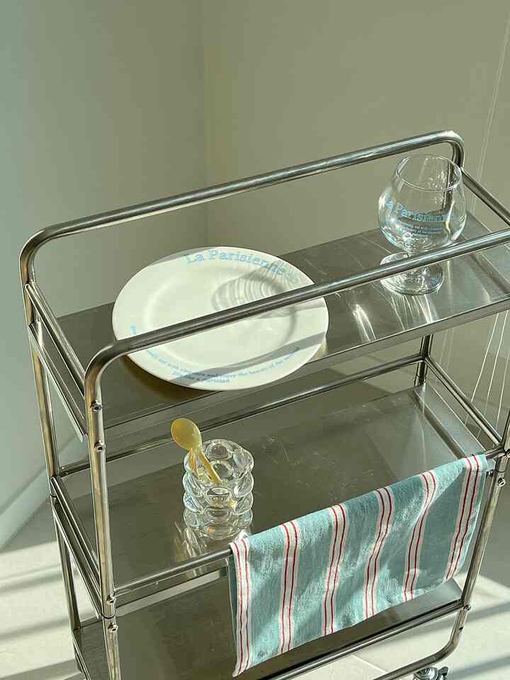 Stainless steel food trolley featuring French mood lettering plate and goblet placed neatly in a kitchen cart