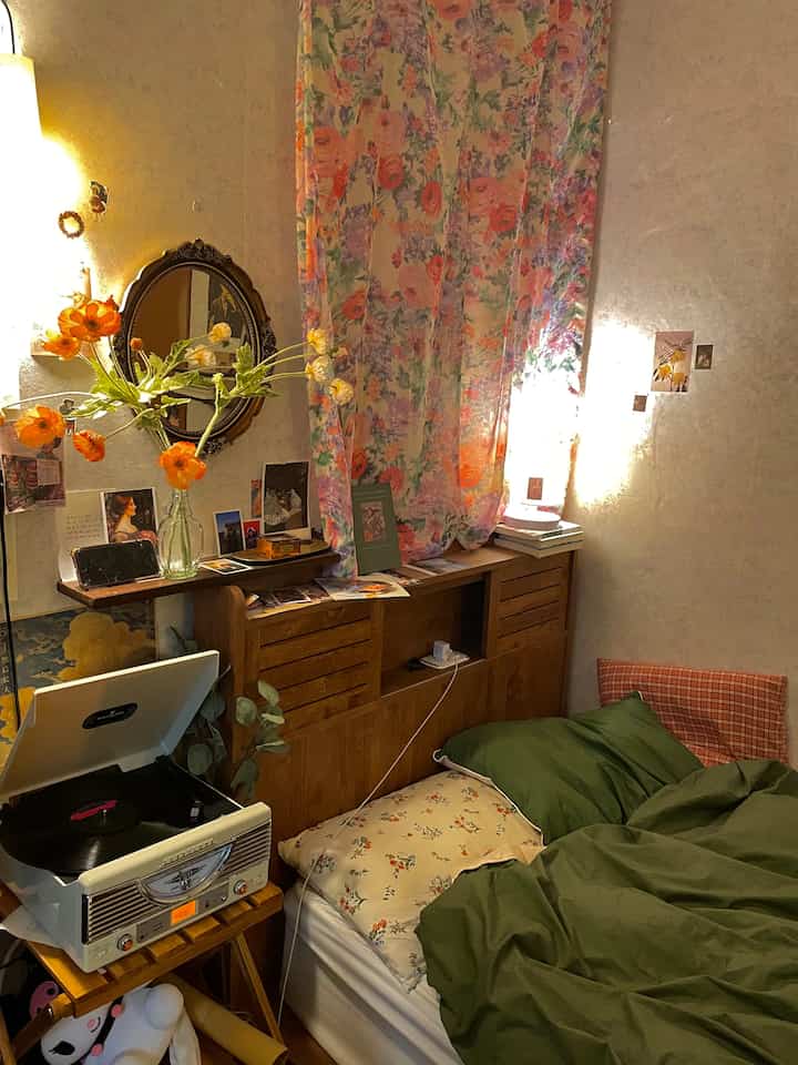 Cozy bedroom with warm wood tone and floor lamp, featuring vintage floral pattern curtains and an ornate mirror