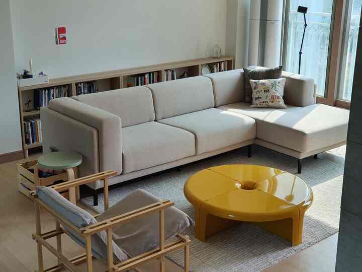 Bright natural color and wood tone living room featuring a beige sofa and yellow coffee table in a simple modern setting