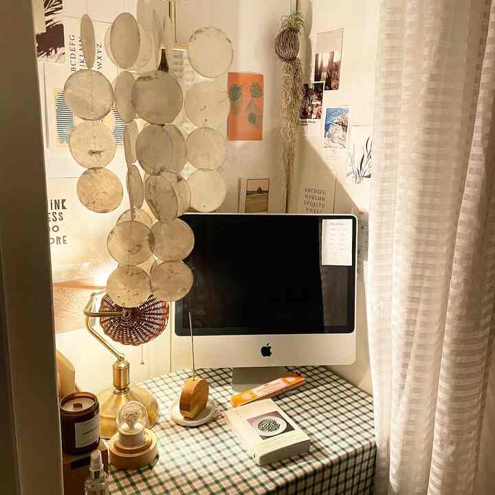 Natural toned compact home office featuring a plaid tablecloth, hanging mobile, and a computer on a cozy desk setup