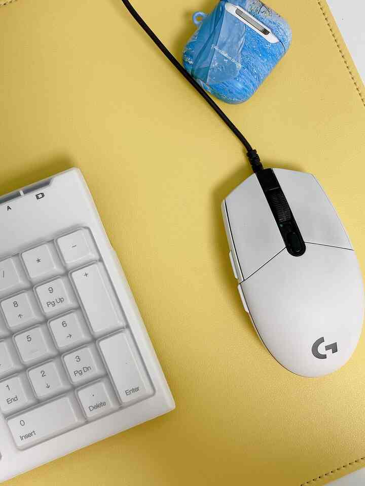 Bright yellow leather desk mat featuring a white gaming mouse and keyboard in a home office setting