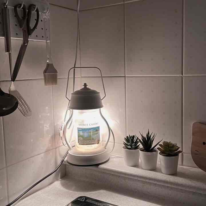 White tiled kitchen corner featuring succulent plants and a Yankee Candle warmer with soft ambient lighting