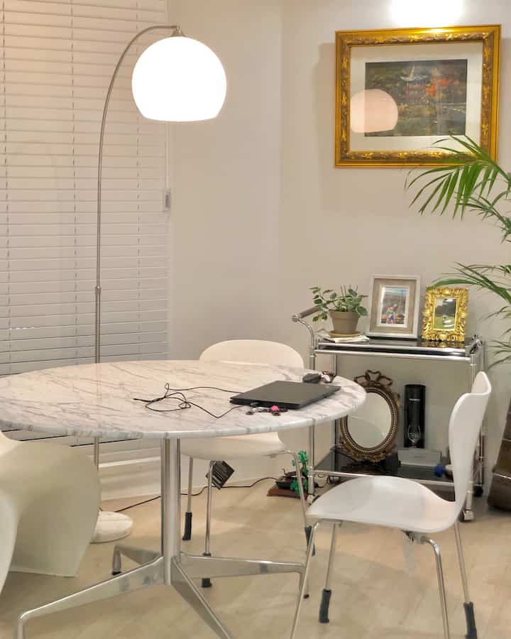 A modern and clean living-dining area in white and natural tones featuring FRITZ HANSEN chairs and a marble dining table