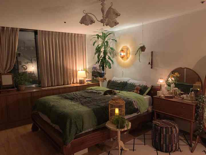 Cozy bedroom featuring warm beige curtains, wooden furniture, and green plants with soft lighting