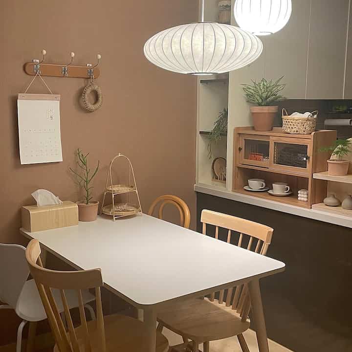 Natural color and brown toned dining room featuring white dining table and wooden chairs in cozy cafe style setting