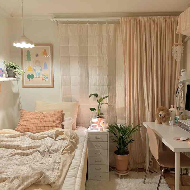 A cozy bedroom in beige and ivory tones featuring a bed, desk, and curtains arranged harmoniously