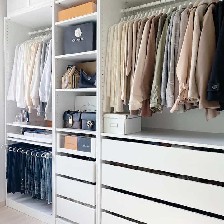 White-toned tidy walk-in closet featuring modern wardrobes and neatly arranged autumn clothes