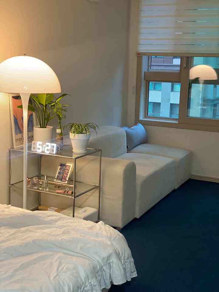 White and dark blue toned bedroom featuring a sofa and floor lamp in a cozy natural setting