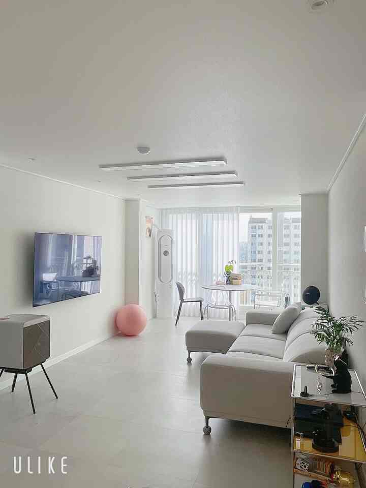 Bright white-toned living and dining room featuring a round table and modern gray sofa in a clean, minimal space
