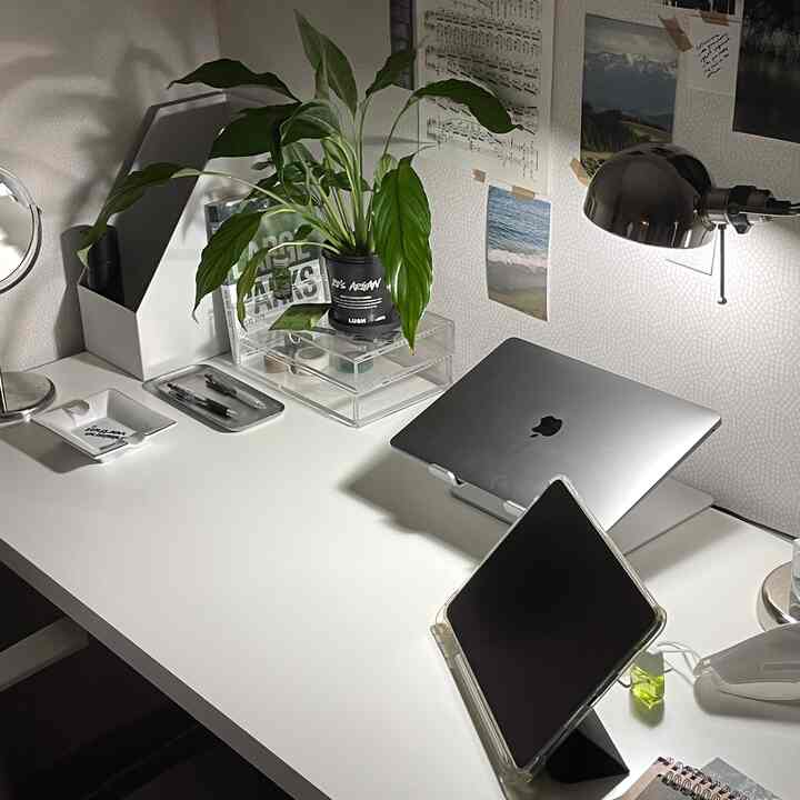 Minimal white-toned home office space featuring a desk with laptop, tablet, and transparent acrylic pen tray, creating a clean working environment