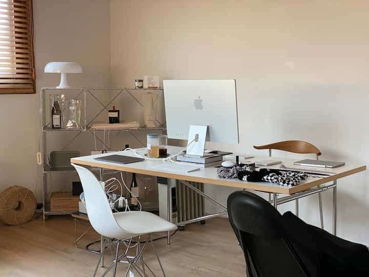 White and natural color toned home office featuring Eames chair and modern desk with organized workspace