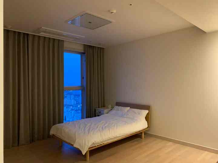 Beige natural-toned bedroom featuring custom blackout curtains and a simple bed creating a cozy atmosphere